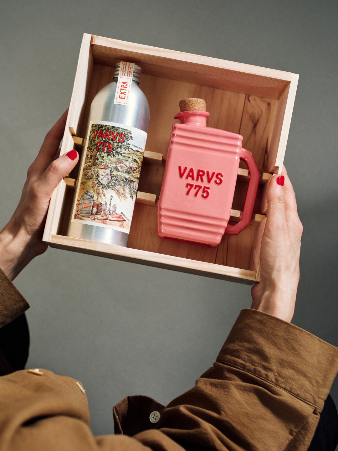 Hands holding open wooden presentation box with bottles against gray background, Varus 775 by Olssøn Barbieri, Lübbecke, Olssøn Barbieri / Varus Brennerei, Lübbecke, Germany