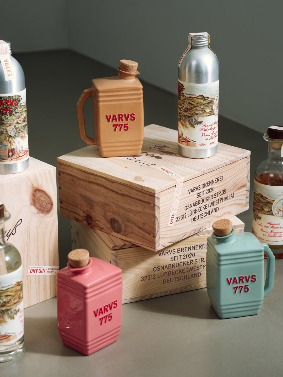 Pastel handled bottles and decorated clear bottles arranged around wooden box, Varus 775 by Olssøn Barbieri, Lübbecke, Olssøn Barbieri / Varus Brennerei, Lübbecke, Germany