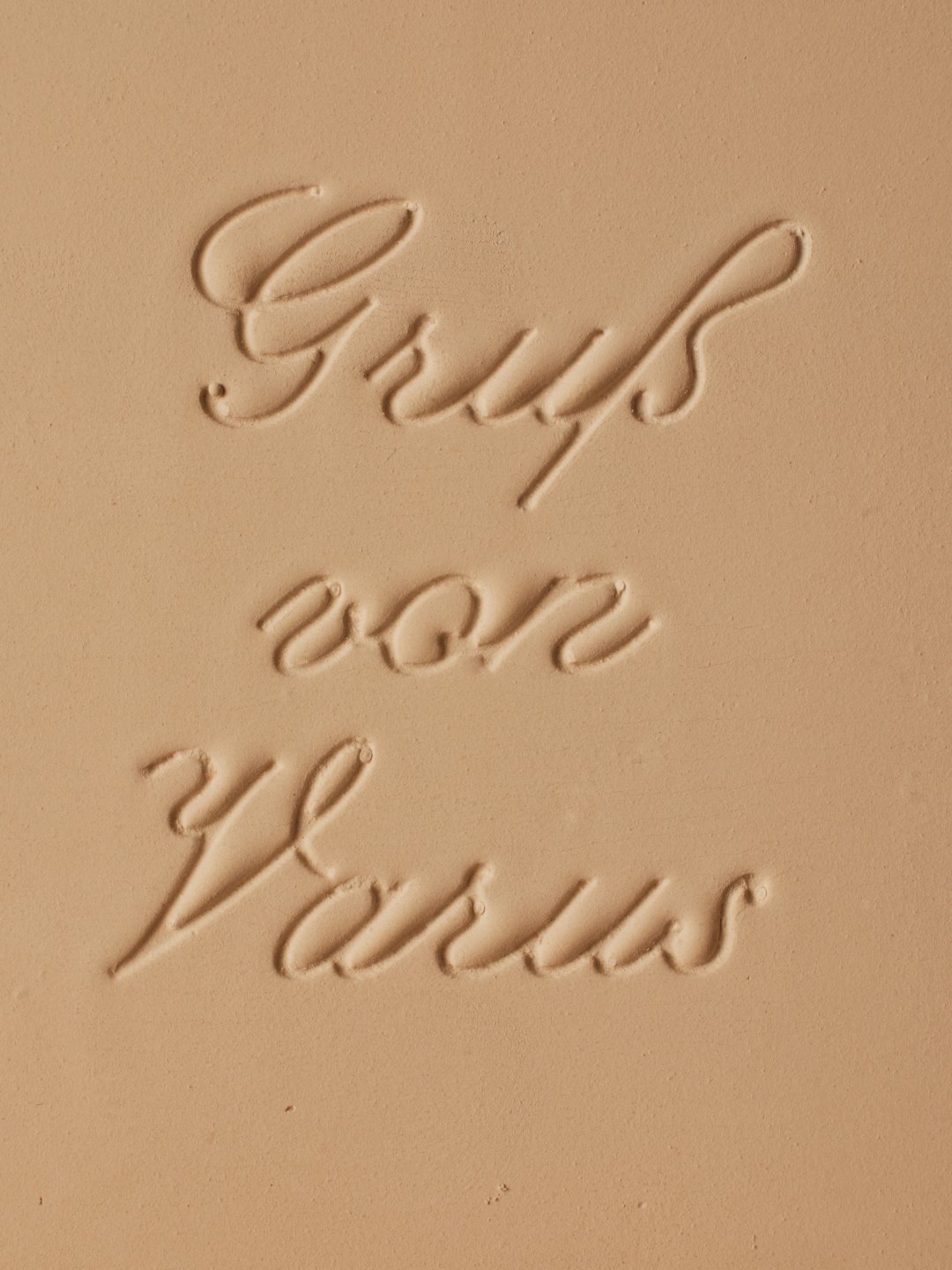 Close-up of embossed cursive lettering on matte tan surface, Varus 775 by Olssøn Barbieri, Lübbecke, Olssøn Barbieri / Varus Brennerei, Lübbecke, Germany