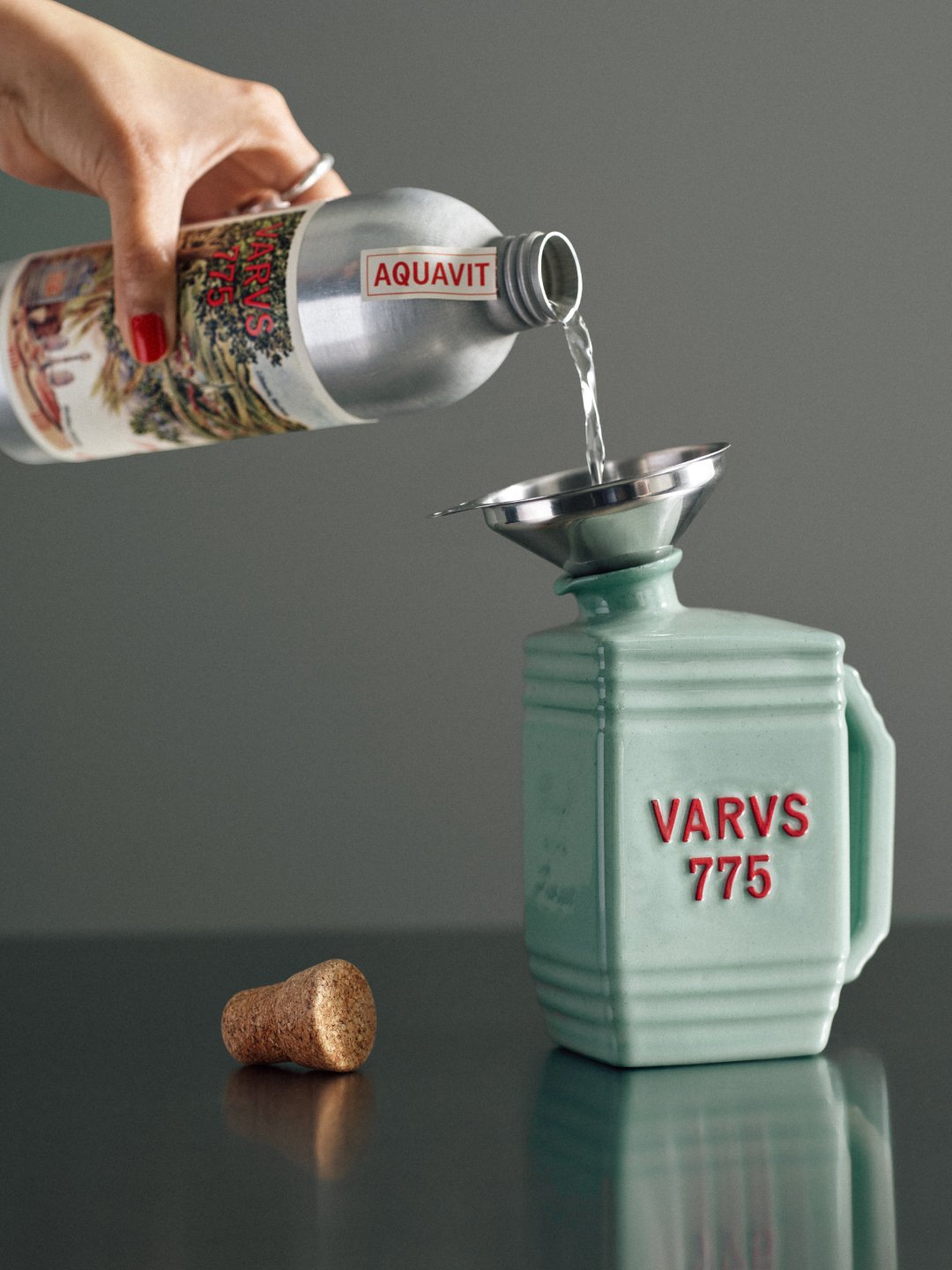 Hand pouring clear liquid through funnel into pale green bottle, Varus 775 by Olssøn Barbieri, Lübbecke, Olssøn Barbieri / Varus Brennerei, Lübbecke, Germany